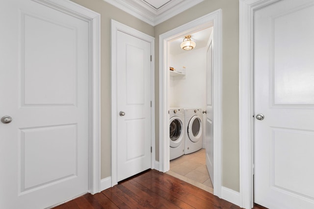 laundry room with dark wood-type flooring, ornamental molding, washing machine and dryer, and laundry area