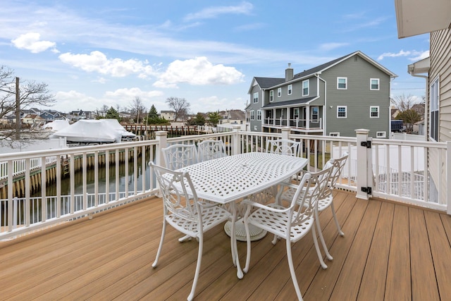 wooden deck with a residential view, outdoor dining area, and a water view