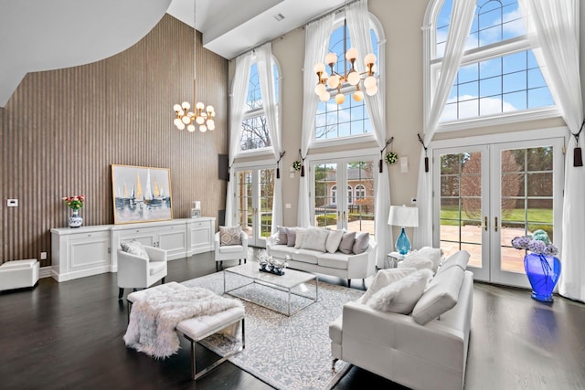 living room featuring french doors, a notable chandelier, a high ceiling, and dark wood finished floors