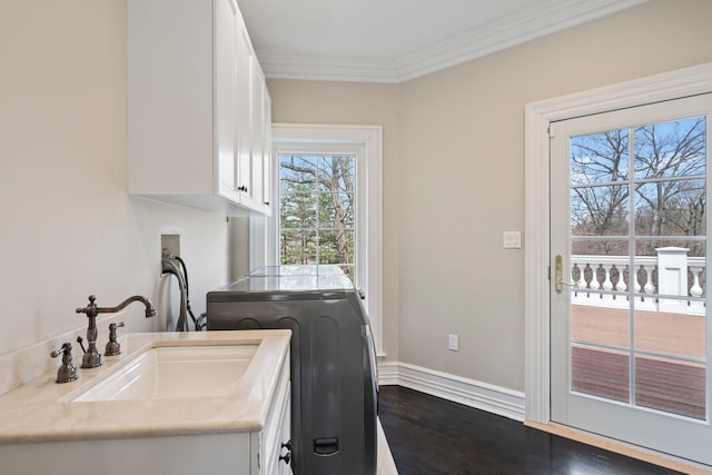 laundry area featuring dark wood-style flooring, ornamental molding, washer / dryer, cabinet space, and a sink
