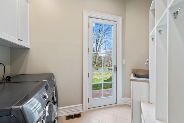 washroom featuring a healthy amount of sunlight, washing machine and dryer, a sink, and cabinet space