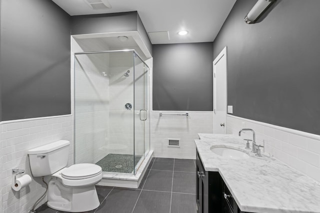 full bathroom featuring visible vents, toilet, tile walls, vanity, and a wainscoted wall