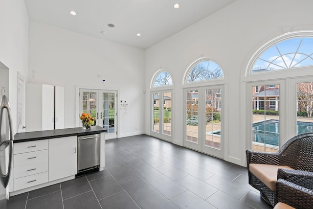 interior space with french doors, dark tile patterned floors, recessed lighting, and a high ceiling