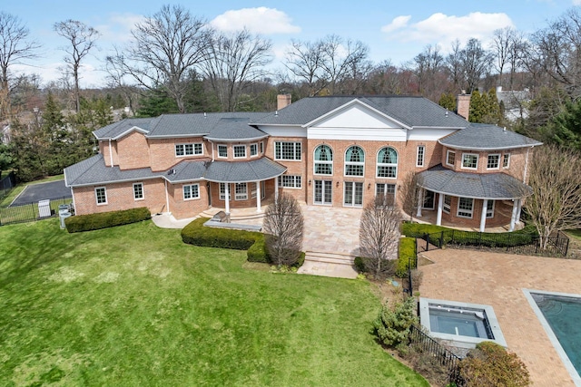 rear view of house featuring a patio, a chimney, a yard, and brick siding