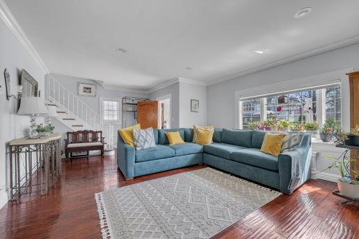 living room featuring stairs, crown molding, and wood finished floors