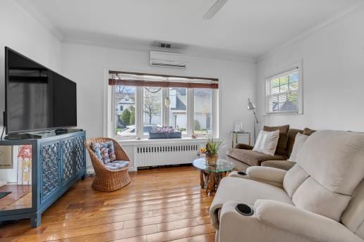 living room featuring crown molding, hardwood / wood-style floors, a wall unit AC, and radiator