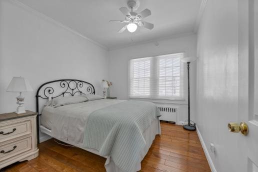 bedroom featuring radiator, wood finished floors, baseboards, and ornamental molding
