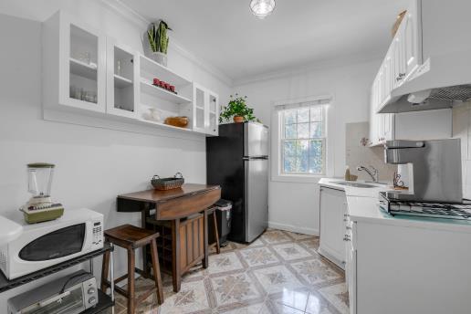 kitchen featuring white cabinets, a sink, freestanding refrigerator, white microwave, and light countertops