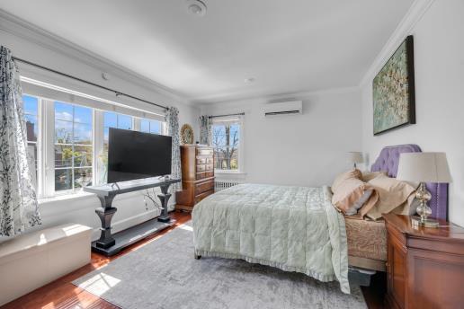 bedroom featuring radiator heating unit, wood finished floors, a wall unit AC, and ornamental molding