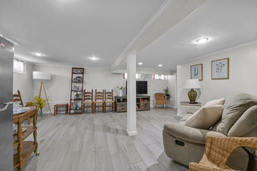 basement featuring baseboards, light wood-style flooring, a healthy amount of sunlight, and crown molding