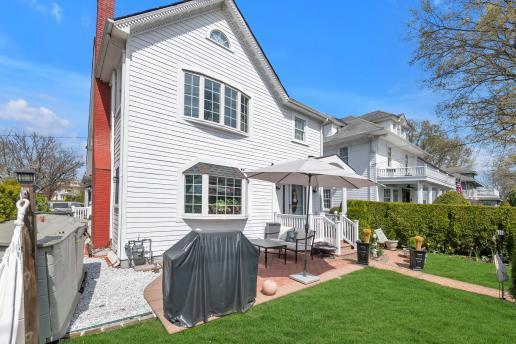 back of property with a chimney, a patio, and a lawn