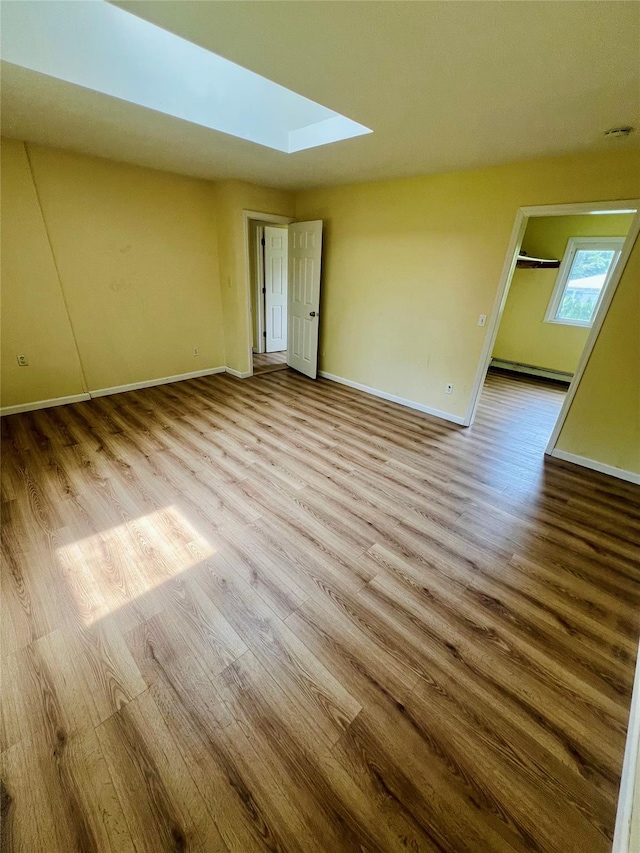 7 Murray Ln, Coram, NY 11727 - spare room with wood finished floors, a skylight, and a baseboard radiator