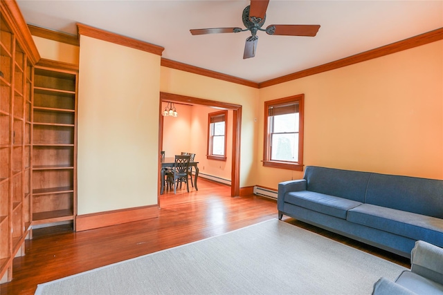 living area with crown molding, ceiling fan, baseboards, wood finished floors, and a baseboard heating unit