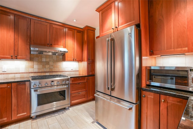 kitchen featuring under cabinet range hood, stainless steel appliances, brown cabinetry, and tasteful backsplash