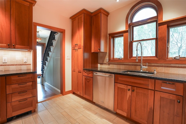 kitchen featuring a sink, dark stone counters, dishwasher, and brown cabinets