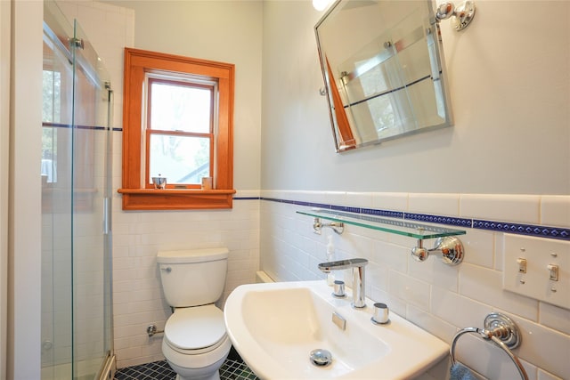 bathroom featuring a sink, toilet, a wainscoted wall, tile walls, and a shower stall
