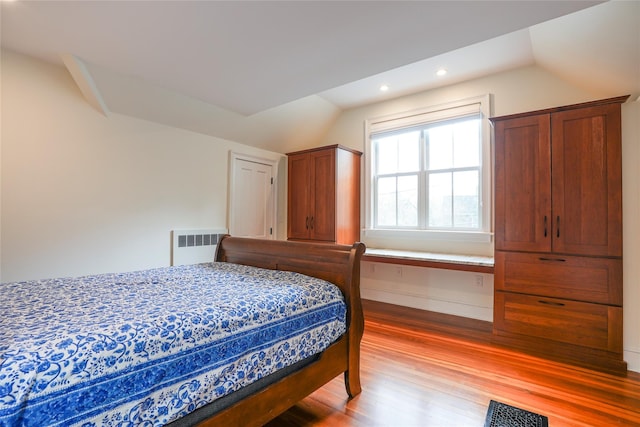 bedroom with radiator, recessed lighting, vaulted ceiling, light wood-type flooring, and visible vents