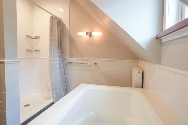 full bath featuring a bathtub, curtained shower, and a wainscoted wall