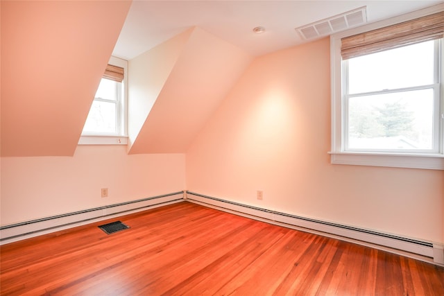 additional living space with visible vents, a baseboard radiator, lofted ceiling, and wood finished floors