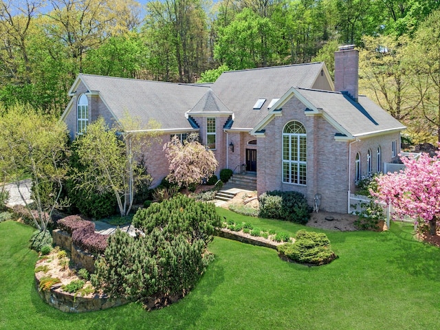view of front of home featuring brick siding, a chimney, and a front lawn