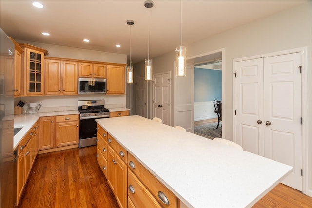 kitchen featuring a center island, light countertops, dark wood-style floors, and stainless steel appliances