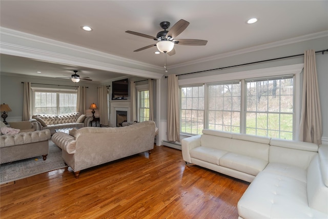 living area with a baseboard heating unit, a ceiling fan, and ornamental molding