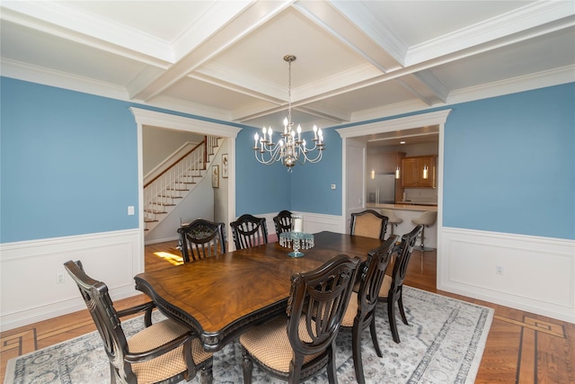 dining room featuring a notable chandelier, stairs, wainscoting, beamed ceiling, and coffered ceiling