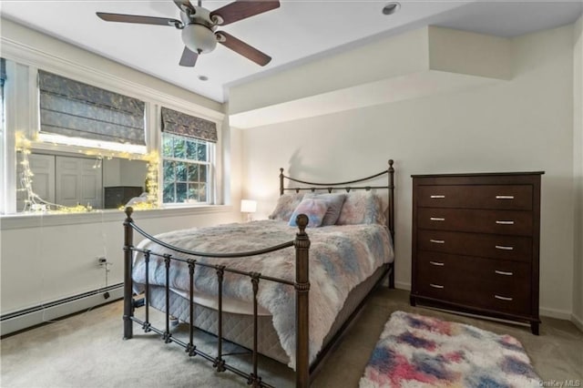 carpeted bedroom with ceiling fan, a baseboard heating unit, and baseboards