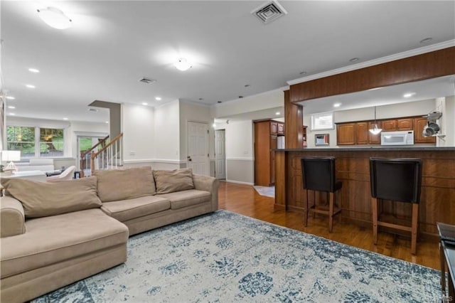 living room featuring crown molding, visible vents, stairway, recessed lighting, and wood finished floors