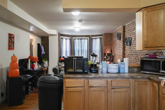 138 S Clark St, Newburgh, NY 12550 - kitchen featuring stainless steel microwave, dark countertops, wood finished floors, and brick wall