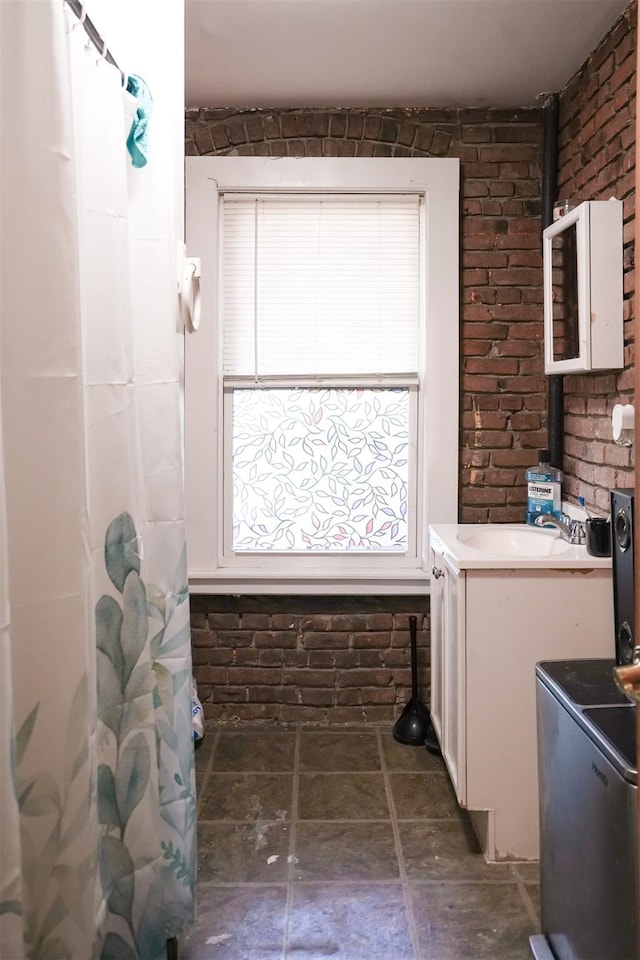 138 S Clark St, Newburgh, NY 12550 - bathroom with a shower with shower curtain, stone finish floor, vanity, and brick wall