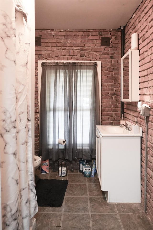138 S Clark St, Newburgh, NY 12550 - bathroom featuring brick wall, vanity, tile patterned floors, and toilet