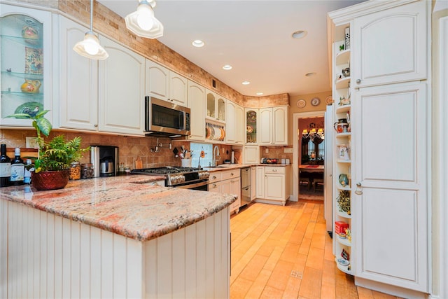 kitchen with open shelves, appliances with stainless steel finishes, a peninsula, decorative backsplash, and light stone counters