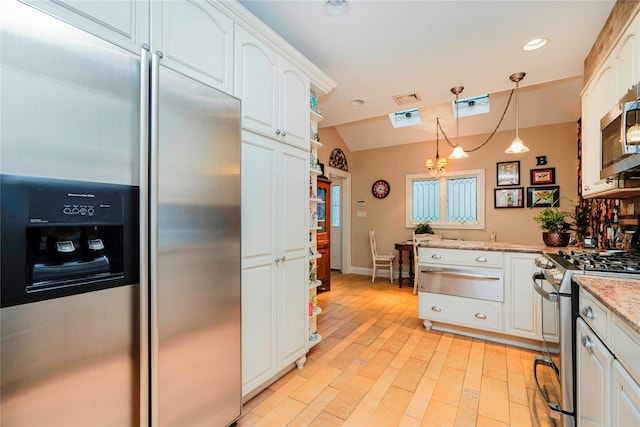 kitchen featuring stainless steel appliances, white cabinets, a warming drawer, and hanging light fixtures