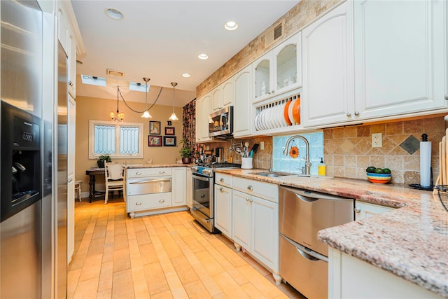 kitchen featuring stainless steel appliances, tasteful backsplash, white cabinetry, and hanging light fixtures