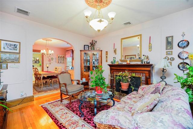 living room with wood-type flooring, arched walkways, a notable chandelier, and visible vents