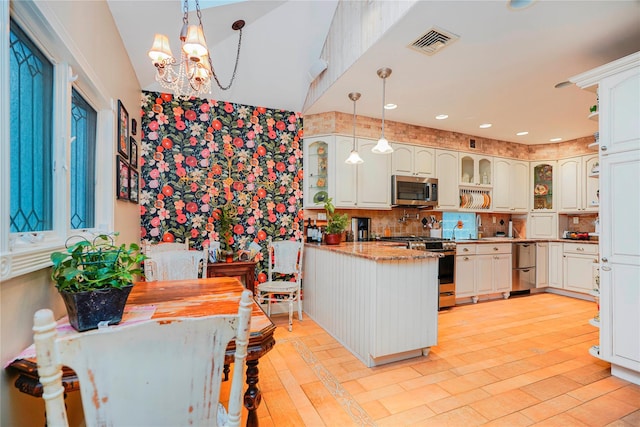 kitchen with a notable chandelier, a peninsula, visible vents, appliances with stainless steel finishes, and pendant lighting