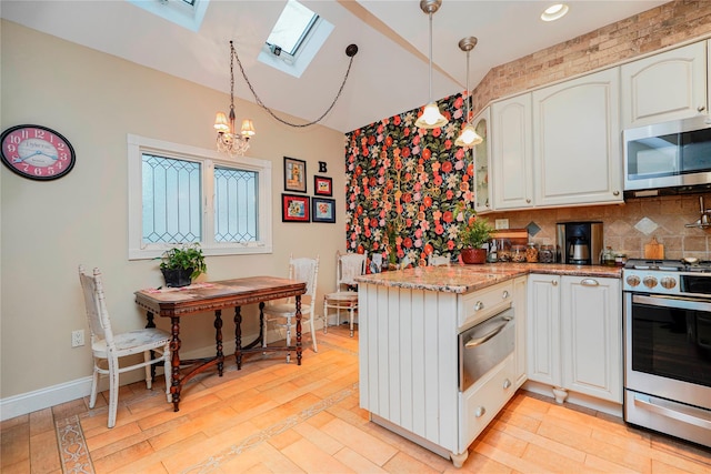 kitchen featuring an inviting chandelier, a peninsula, a warming drawer, stainless steel appliances, and a skylight