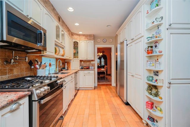kitchen featuring light stone counters, glass insert cabinets, open shelves, decorative backsplash, and stainless steel appliances