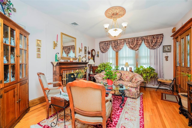 interior space with a chandelier, a fireplace, light wood finished floors, and visible vents