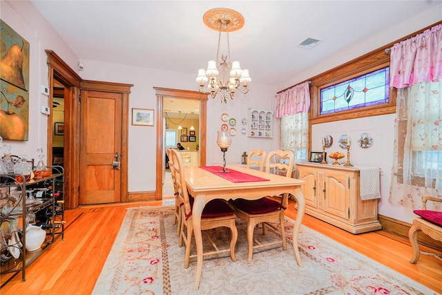 dining space featuring a chandelier, light wood finished floors, visible vents, and a wealth of natural light