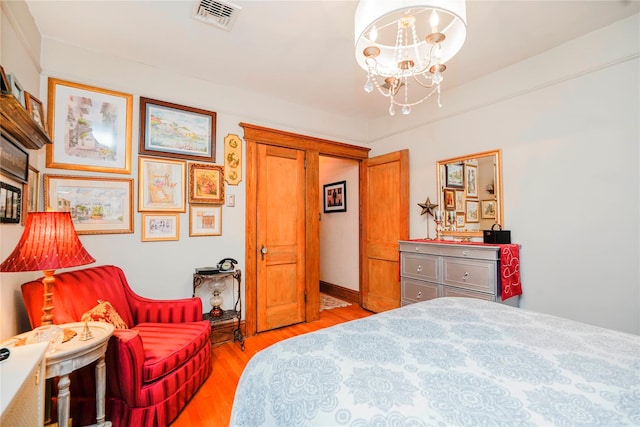 bedroom featuring light wood finished floors, an inviting chandelier, and visible vents