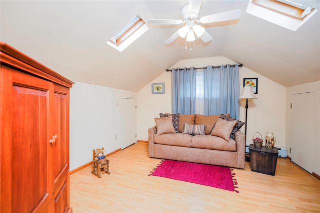 living area featuring vaulted ceiling with skylight, light wood-style flooring, a ceiling fan, and baseboard heating