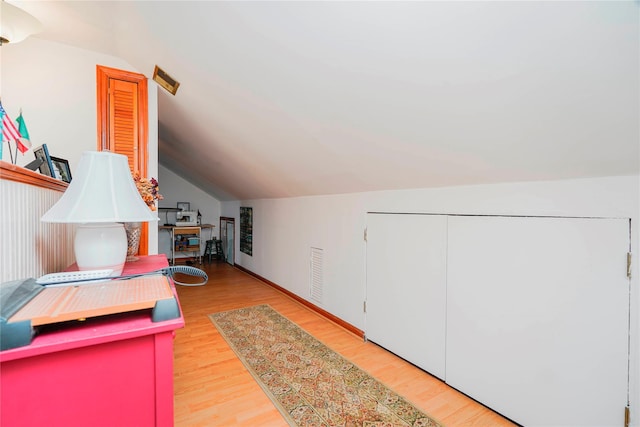 bonus room featuring visible vents, light wood-type flooring, and vaulted ceiling