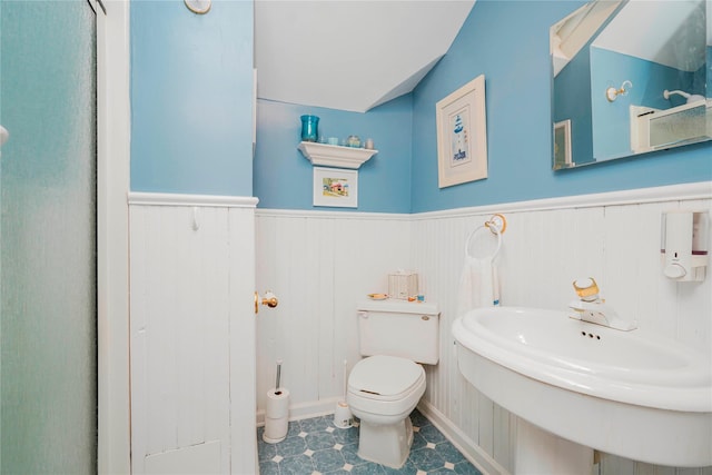 bathroom with toilet, a sink, and a wainscoted wall