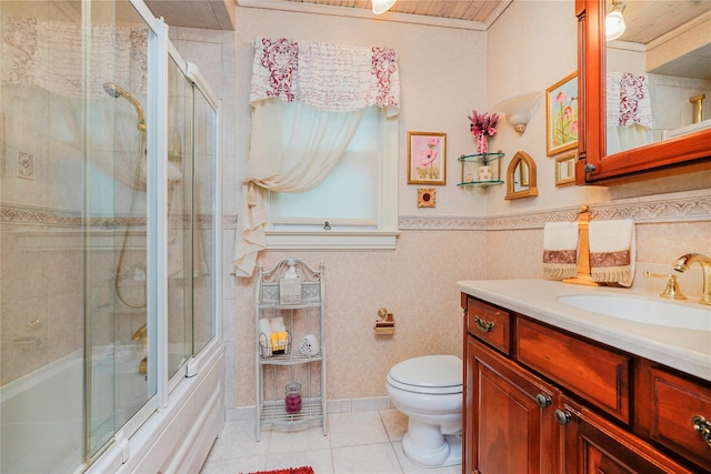 bathroom featuring toilet, tile patterned floors, vanity, and bath / shower combo with glass door