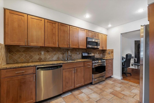 19 James Ct Unit 19, Port Chester, NY 10573 - kitchen with stainless steel appliances, a sink, backsplash, light stone counters, and brown cabinets