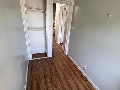 hall with dark wood-style floors and baseboards