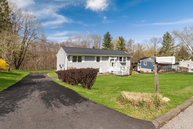 ranch-style house with a front lawn, a chimney, and aphalt driveway