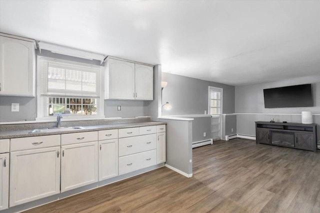 kitchen featuring baseboard heating, a sink, and white cabinetry